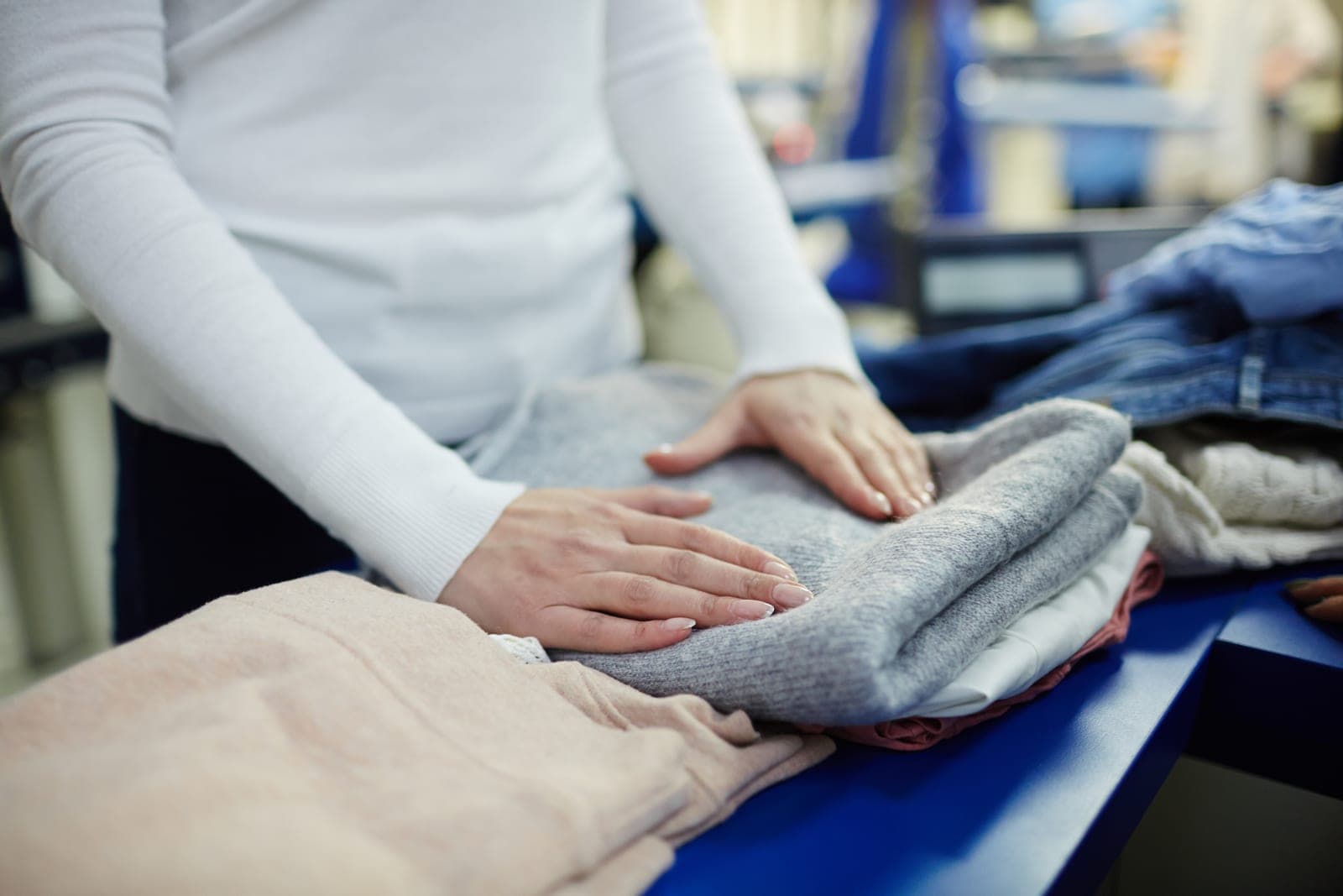 Freshly washed knitwear being folded by hand on a counter