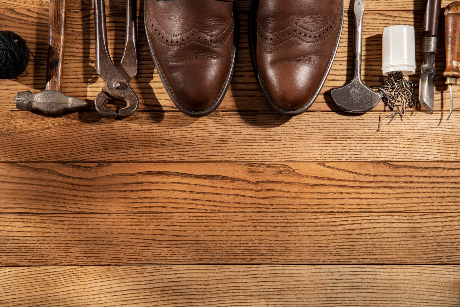 A pair of leather brogues laid out with traditional cobbler's tools
